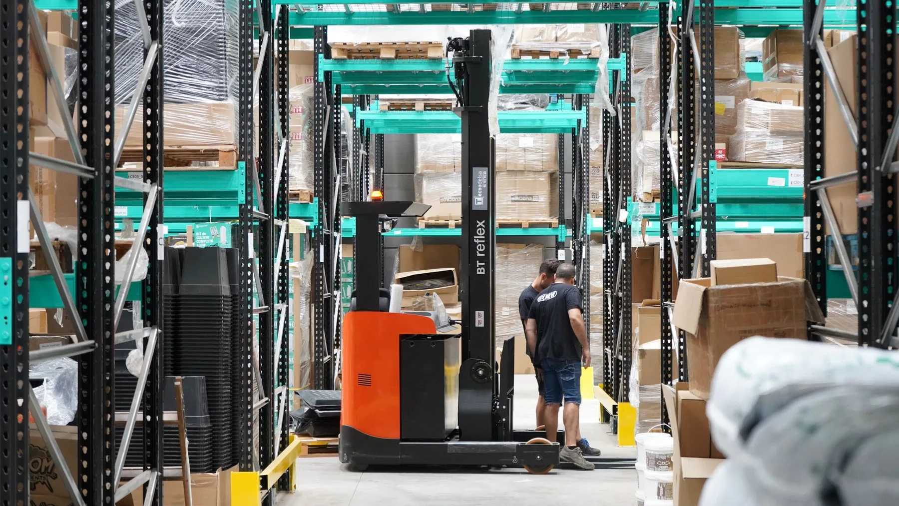 Travail logistique dans une allée d’entreposage avec un chariot élévateur — photographie d’illustration.