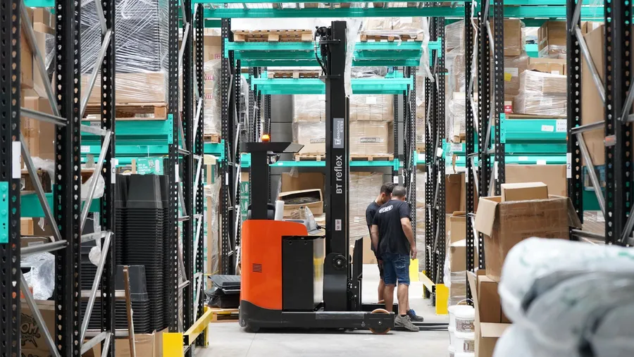 Forklift and goods on warehouse shelves.
